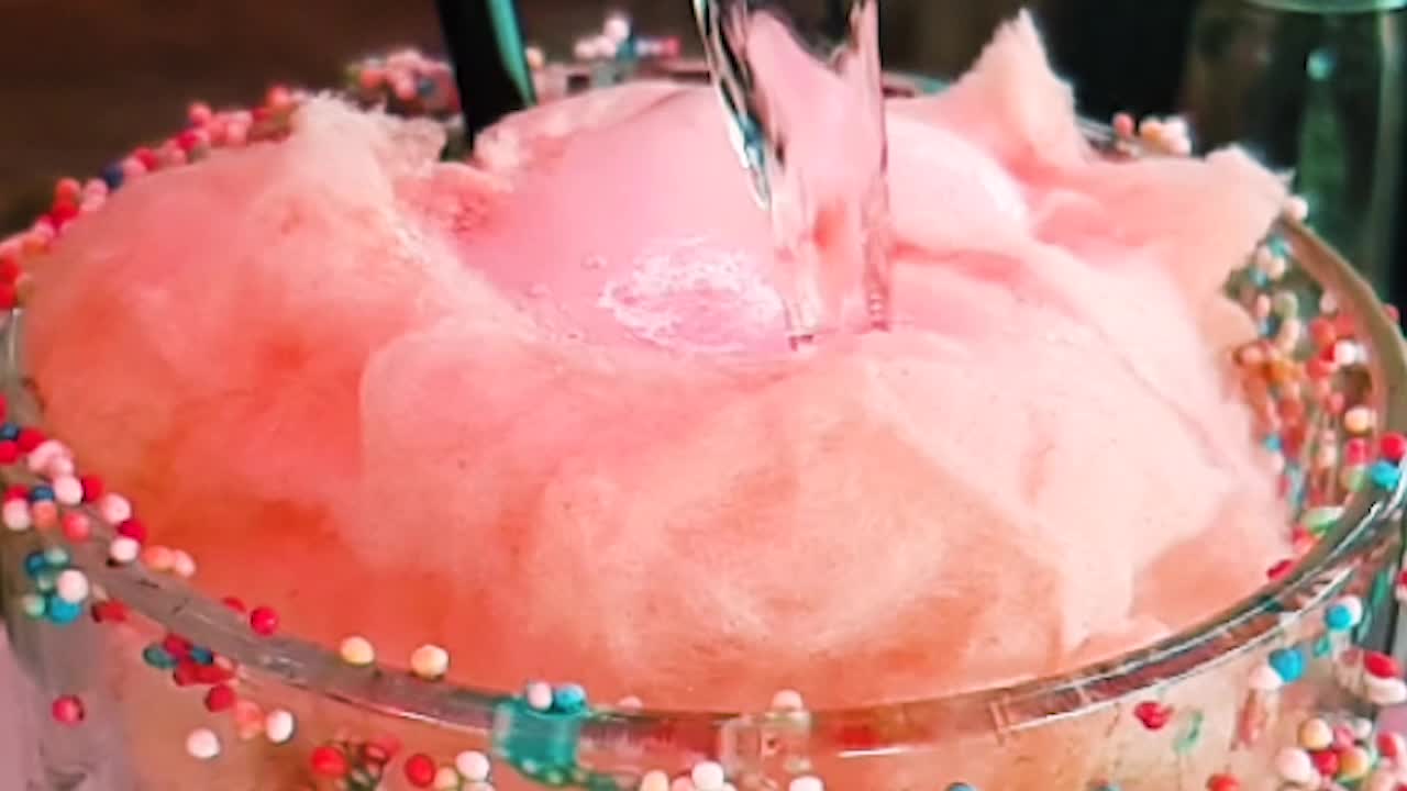 막대에 있는 분홍색 거품으로 가득 찬 유리에 액체를 붓는 매우 느린 동작