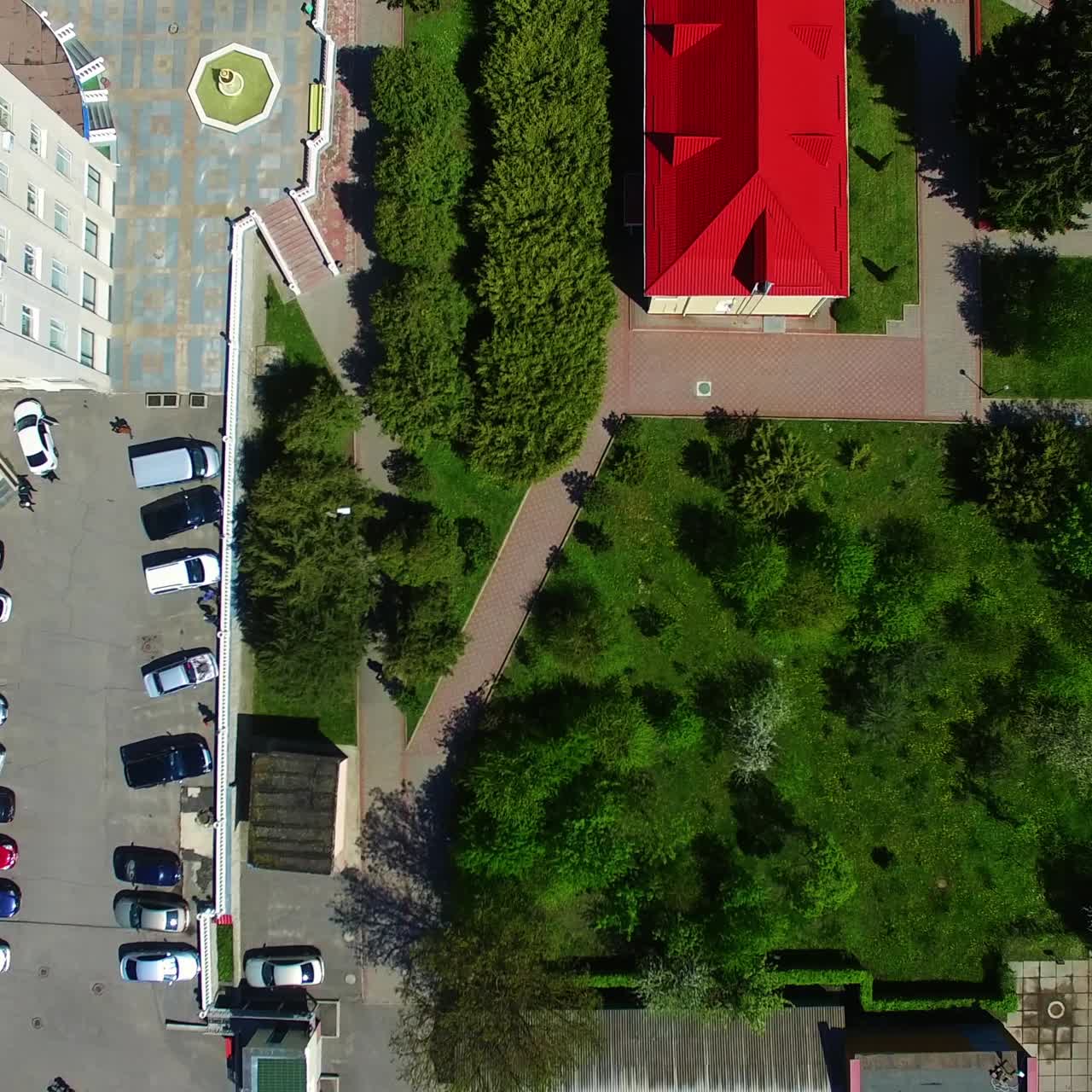 Descending over the residential area with beautiful well-kept territory. Drone footage over the building tops on sunny day