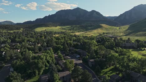 aerial sobre las colinas boscosas de boulder con los picos de las montañas flatirons en el fondo, colorado, ee.uu.