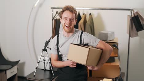 cute curly man holding a cardboard box smiling