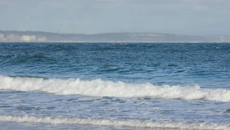 pequeño barco moviéndose frente a costa da caparica cerca del faro de torre do bugio
