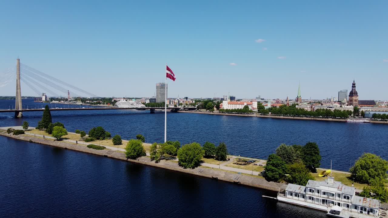 Aerial view of Riga city skyline across Daugava river with waving Latvian flag