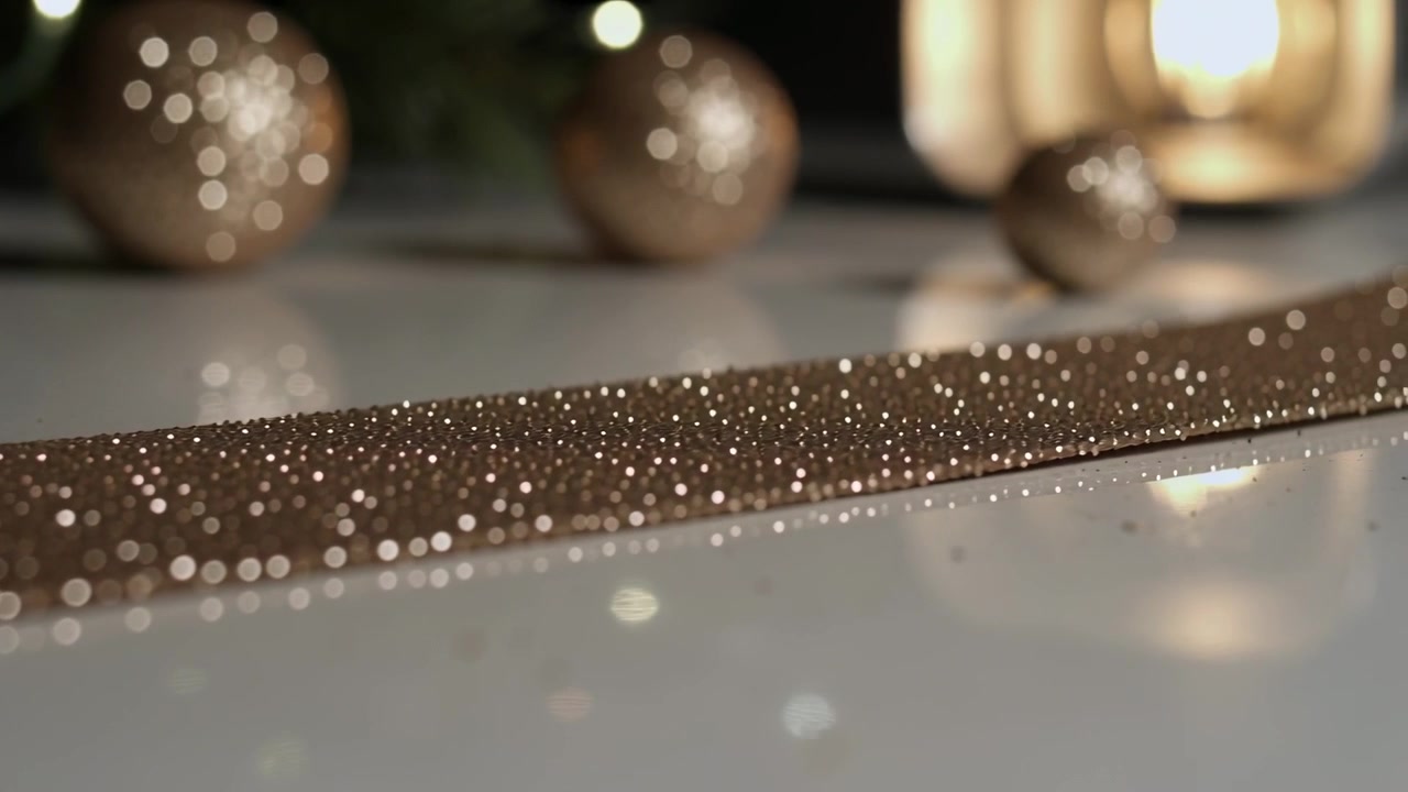 Showing gold glitter strip shining under soft camera shift on glass table, with ornaments and lamp