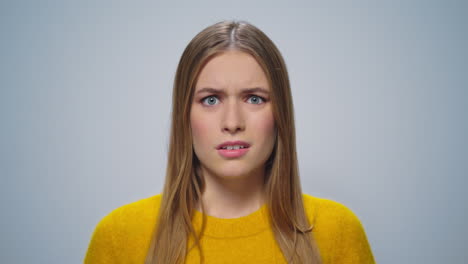 Portrait-of-scared-girl-looking-at-camera-on-grey-background-in-studio.