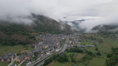 A-breathtaking-high-altitude-pullout-shot-captures-a-small-Spanish-town-nestled-within-the-majestic-Pyrenees-mountains,-offering-a-stunning-panoramic-view