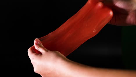 hands manipulating stretchy red slime