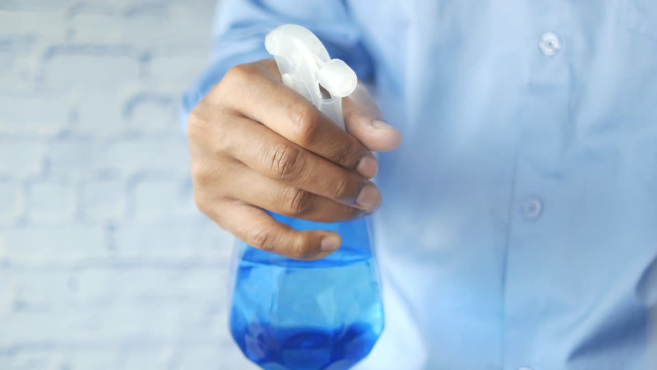 persona que sostiene una botella de spray azul