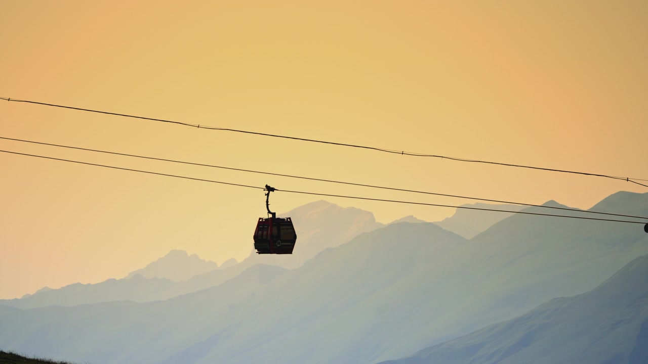 Sagoma di una funivia che si muove su montagne nebbiose al tramonto