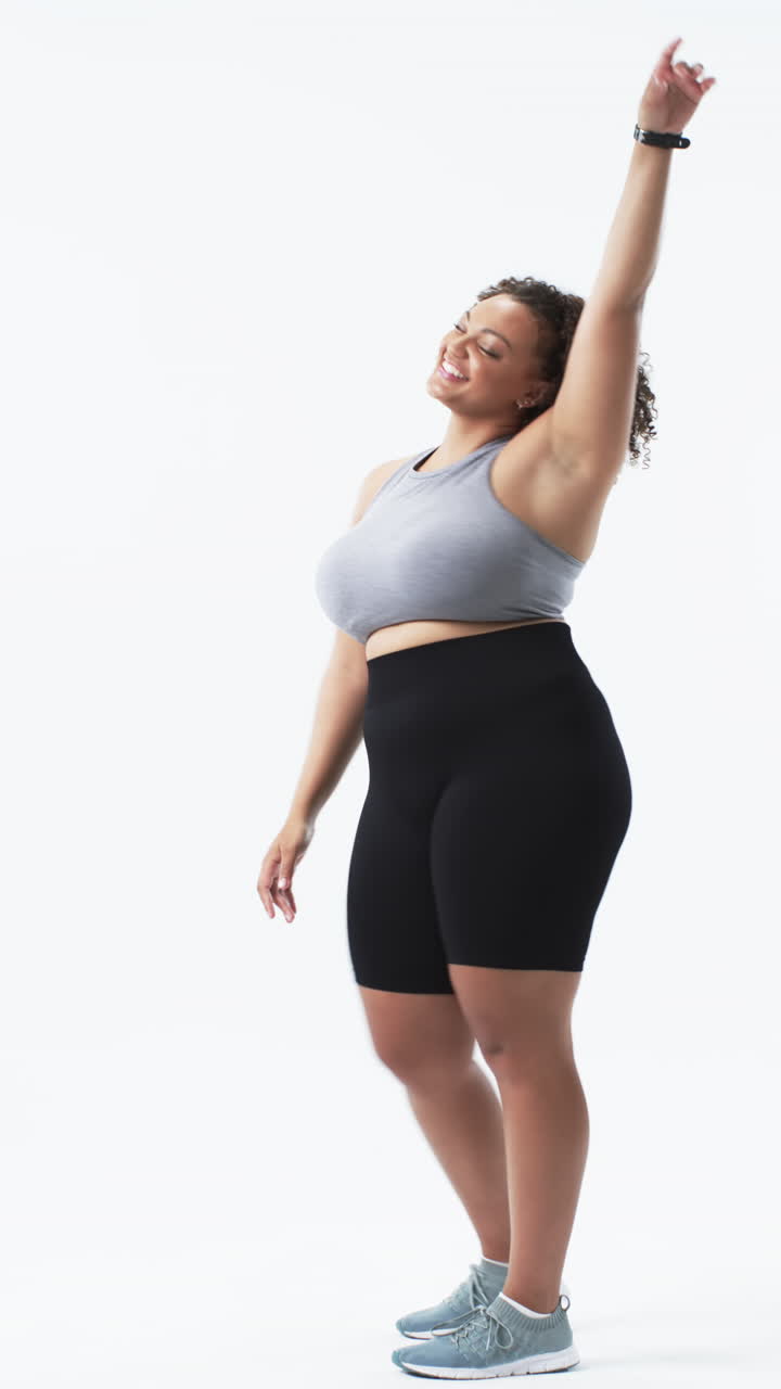 Video verticale: Donna curvy sorridente in abbigliamento sportivo che balla con gioia, promuovendo la positività corporea
