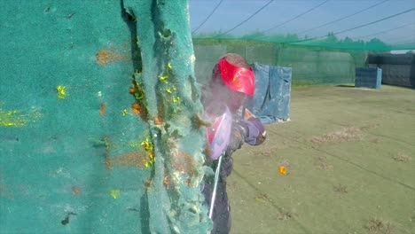 paintballer hiding behind wall while balls exploding on it