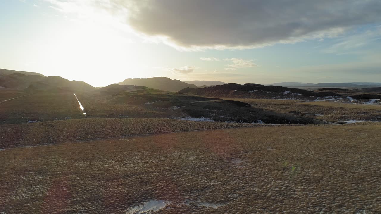 volando hacia la puesta de sol detrás de las montañas de islandia - antena