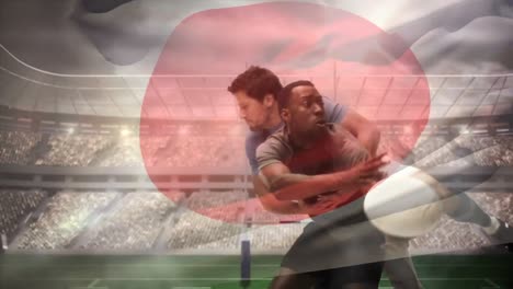 Rugbyspieler-Wirft-Ball,-Während-Er-Von-Einem-Spieler-Angegriffen-Wird,-Und-Japanische-Flagge-Schwenkt-In-Vollen-Stadien