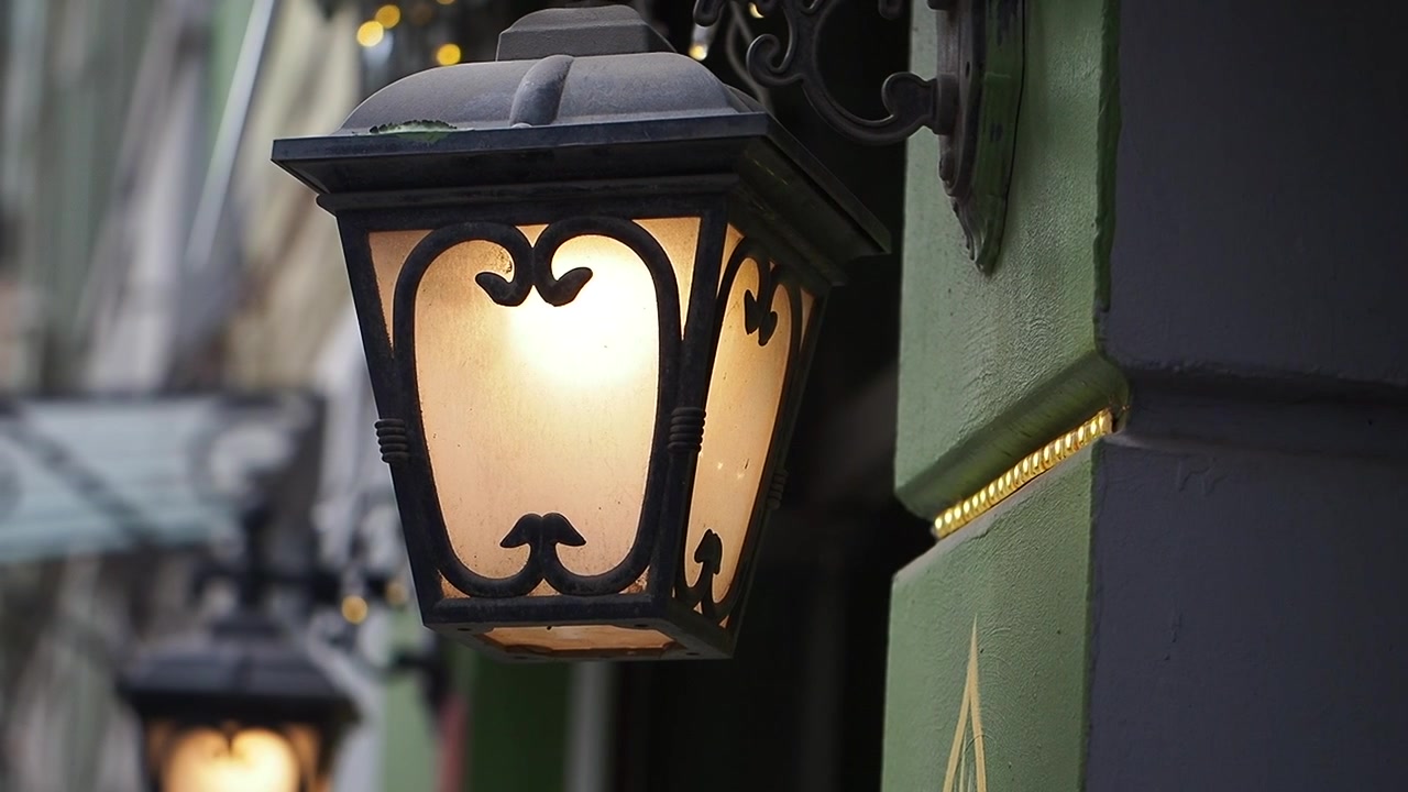 Lanterna da parete in stile vintage illuminata sull'esterno di un edificio verde