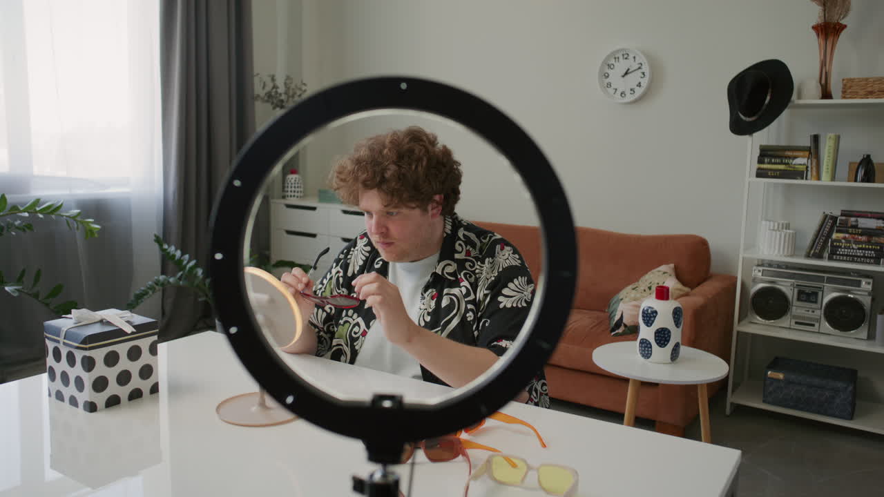Male Blogger Trying on Trendy Sunglasses and Talking to Camera at Home