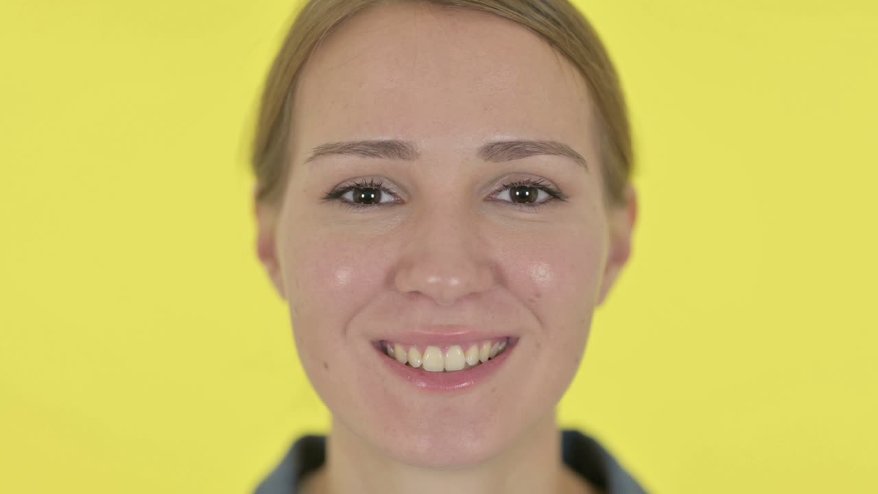 웃는 행복한 젊은 여성의 가까운 얼굴, 노란색 배경