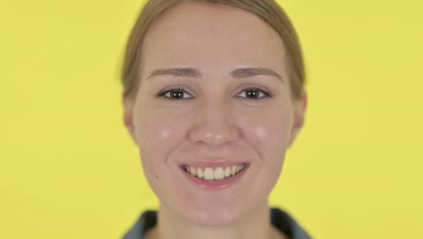 face close up of happy young woman smiling, yellow background
