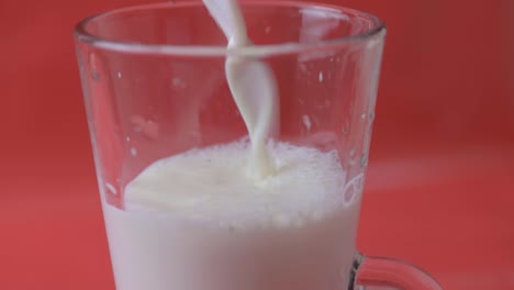 pouring milk into a glass on a red background