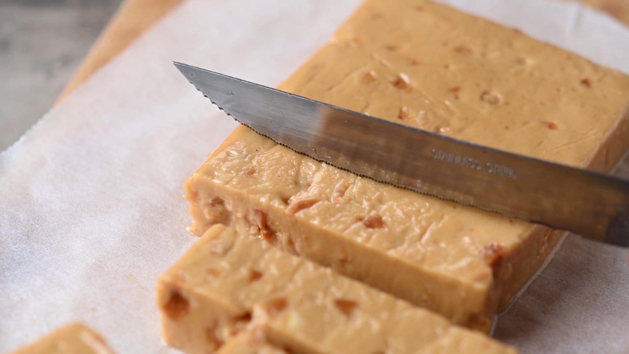 Taglio di una barretta di torrone morbido alle mandorle natalizio