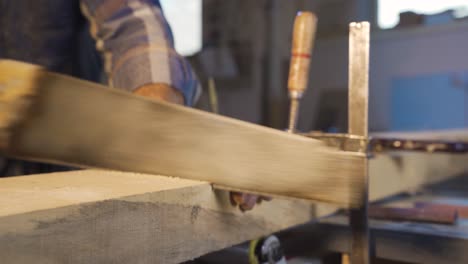 un carpintero está cortando una tabla de madera con una sierra.