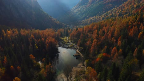 Vista-Aérea-Del-Lago-Tranquilo-Con-Bosques-Otoñales-De-Color-Rojo-Anaranjado-En-El-Valle-De-Val-Di-Mello-En-Lombardía