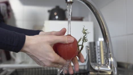 washing red tomatoes at home with water, opening the tap