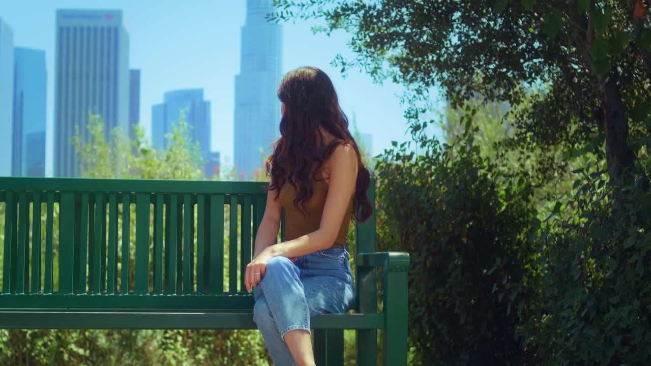 아시안 소녀는 벤치에 드폰을 들고 앉아 하늘을 바라보는 풍경을 즐긴다.