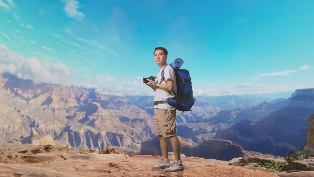 Full Body Side View Of Asian Male Hiker With Mountaineering Backpack Smiling And Holding A Camera In His Hands Then Looking Around While Traveling At The Top Of Mountain