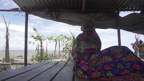 an woman is sitting in front of the river after storm taken away her houses.