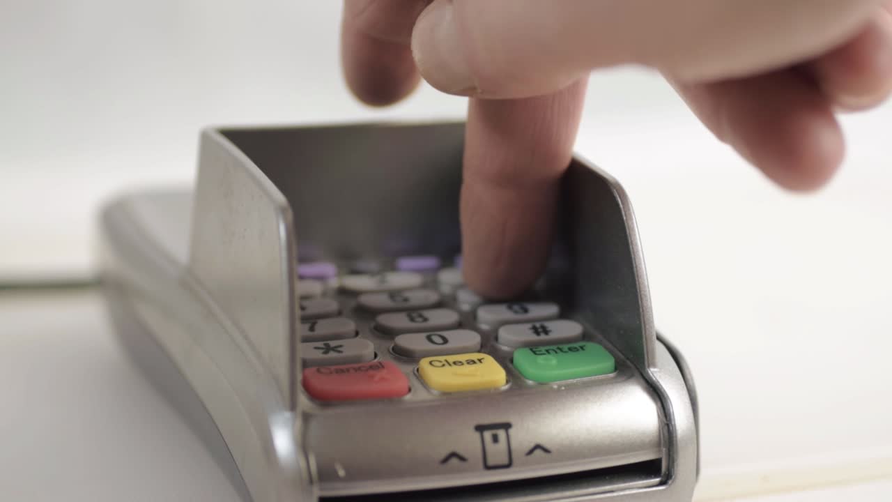 Hand tapping in pin number to pdq payment machine close up shot