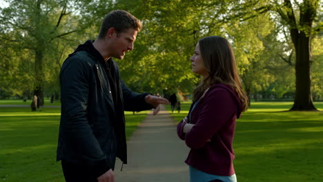 a man and woman having a serious conversation or argument in a park