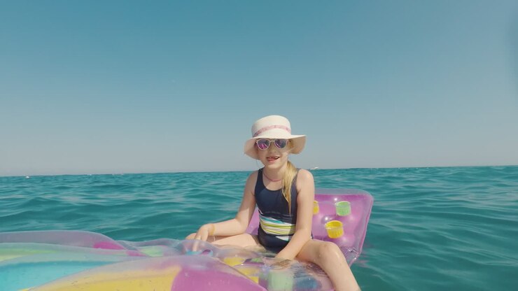 A Girl In A Hat And Sunglasses Floats In The Sea On An Inflatable Mattress Merry Vacation Concept