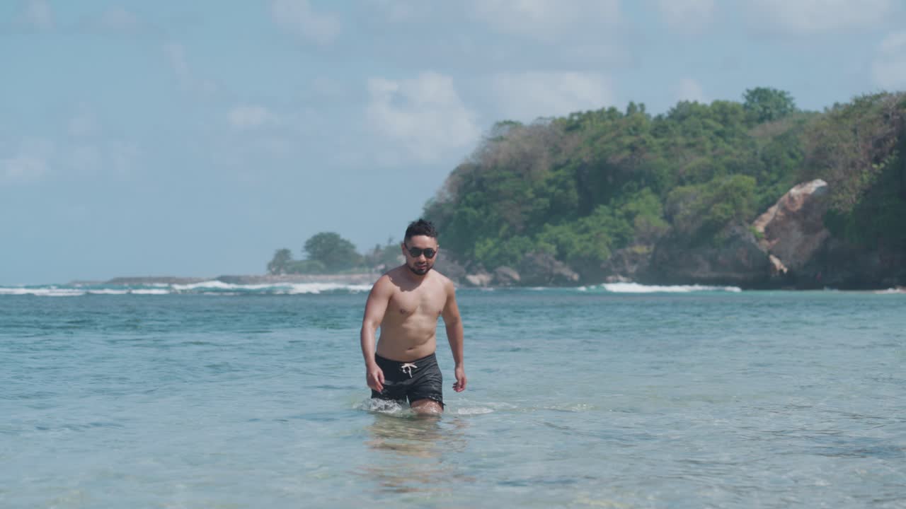 Man walking in shallow water at a tropical beach