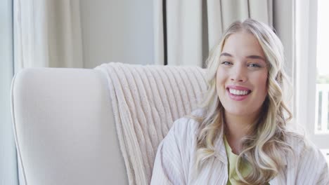 Portrait-of-happy-caucasian-plus-size-woman-sitting-on-armchair-at-home-in-slow-motion