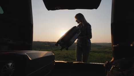 woman puts bags and luggage in the trunk of a car