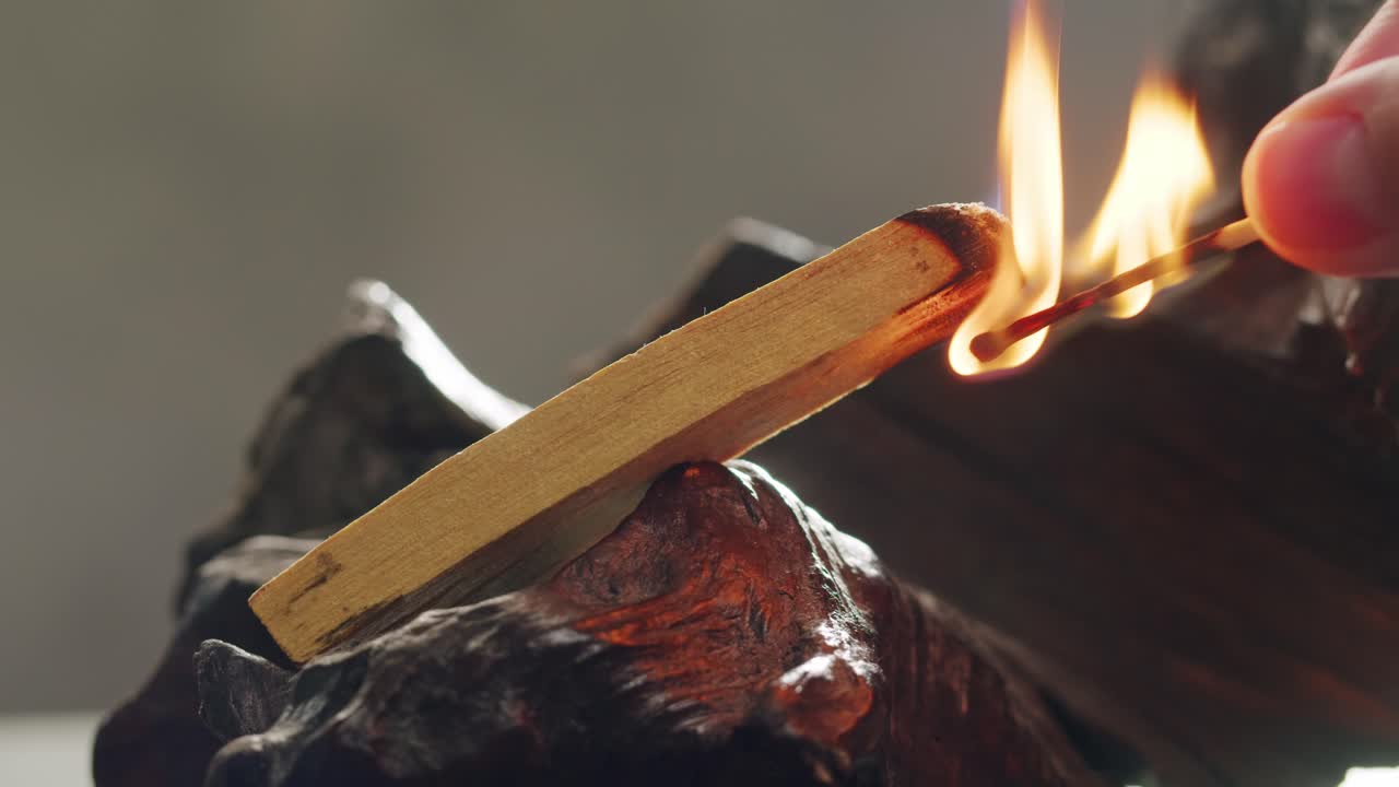 Person holding Palo Santo wood stick in hand, aromatic Palo Santo burning on black background, smoke spreading around, slow motion video clip, high quality 4k close up footage. High quality 4k footage