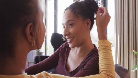 Romantic-biracial-lesbian-couple-relaxing-on-couch-together,-smiling-and-talking,-in-slow-motion