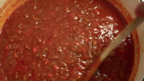 mixing italian bolognese sauce being cooked in a cast iron pot chef stirring the most famous italian sauce