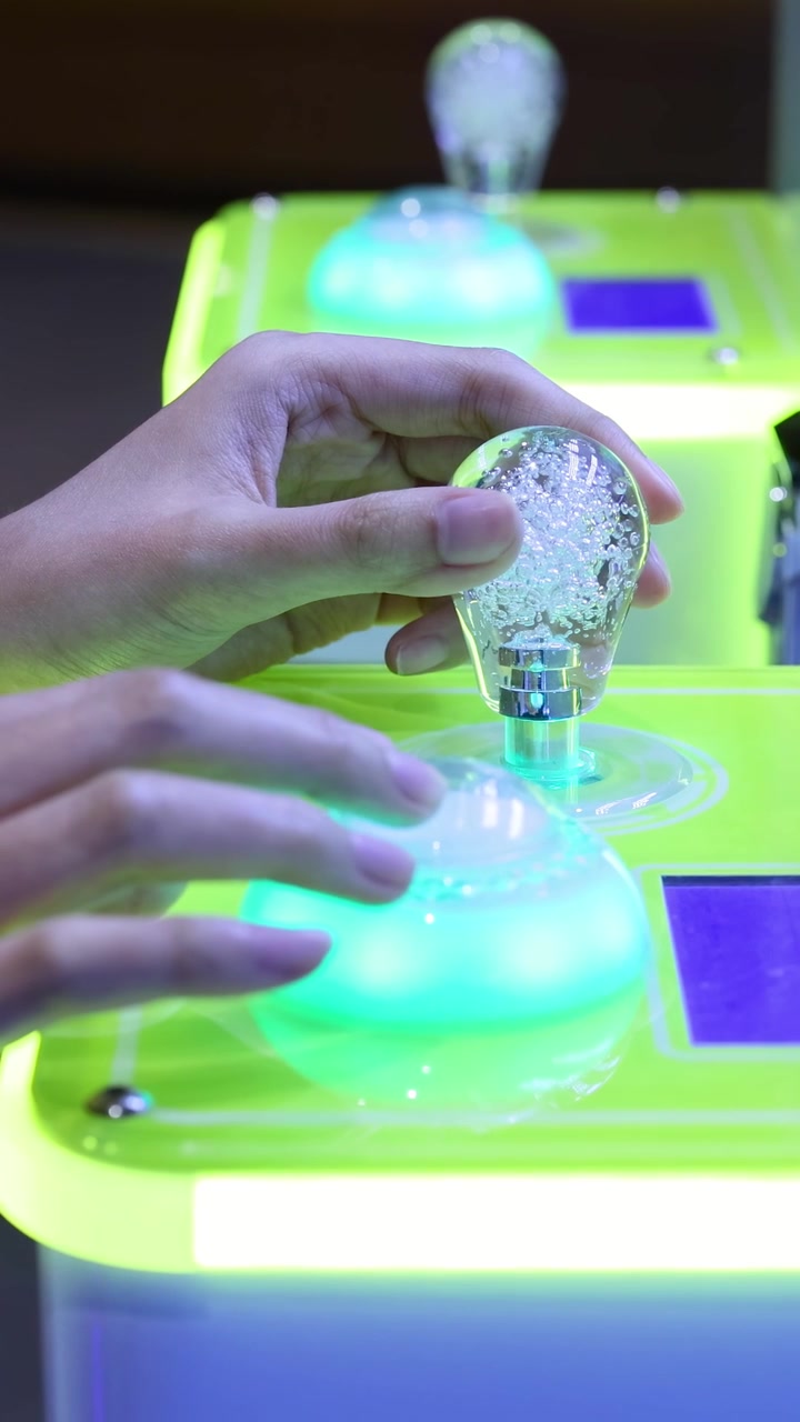Hands interacting with glowing game machine