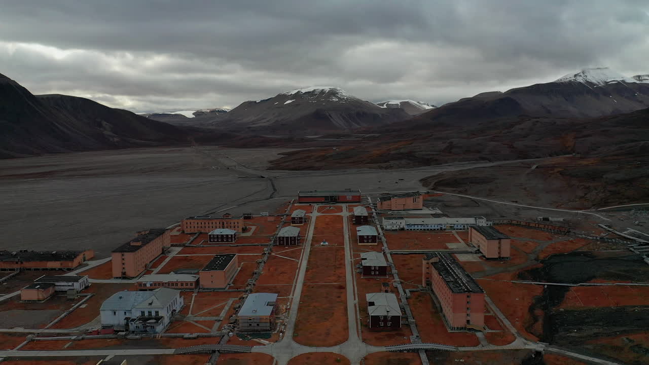 Flying Over The Peaceful Barentsburg Mining Town In Iceland With Mountains In The Background - Aerial Shot