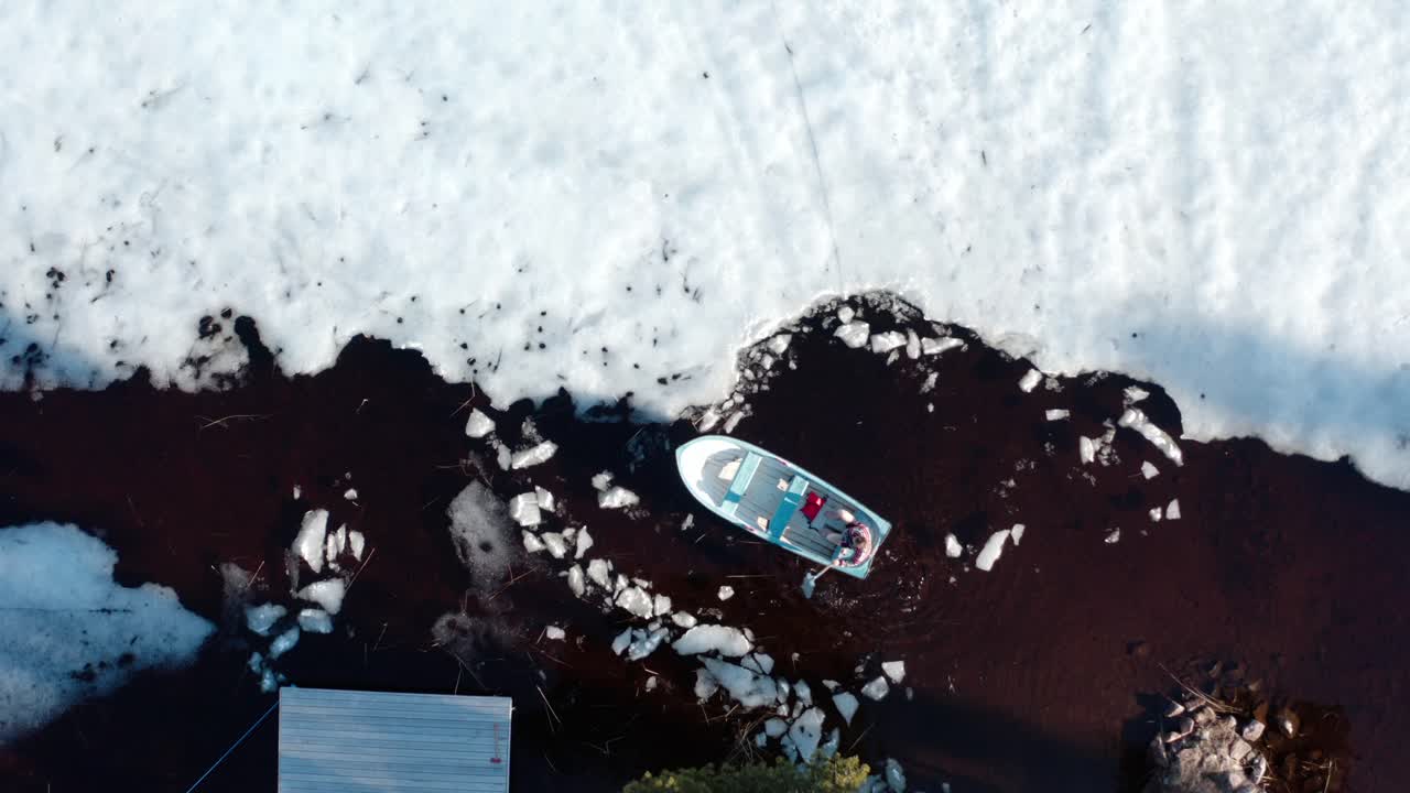Man Rowing Boat Using Shovel On Lake Surrounded With Heap Of Snow