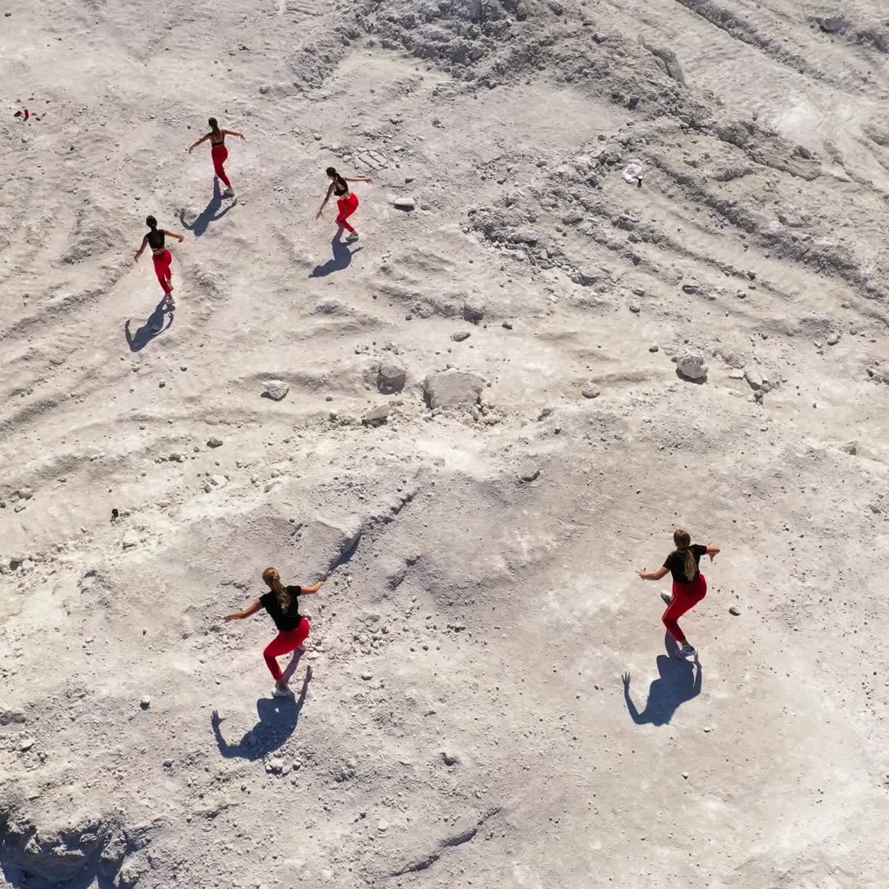 Modern contemporary dance performed by the group of girls. Collective dancing outdoors on the white rocky ground. Top view