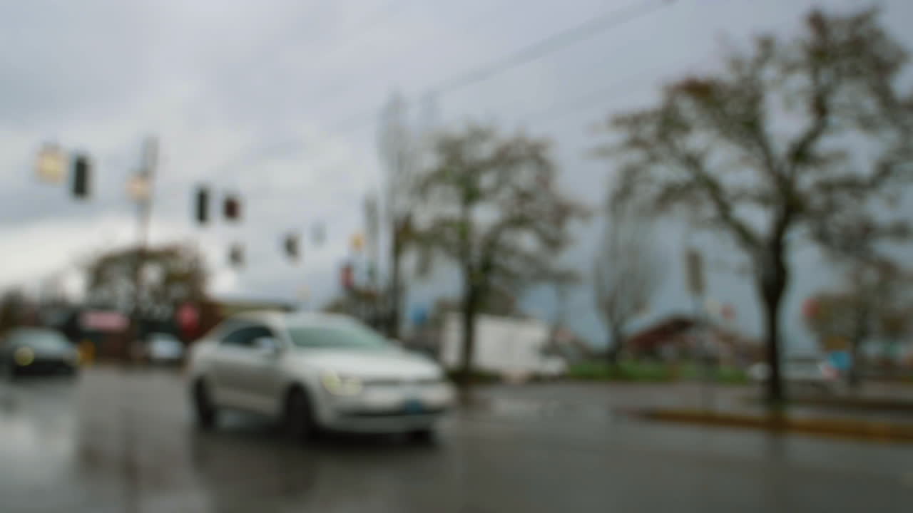 비오는 날씨에 도시의 젖은 미끄러운 도로에서 천천히 운전하는 자동차의 초점을 잃은 샷