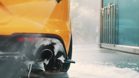 yellow car being washed with pressure washer