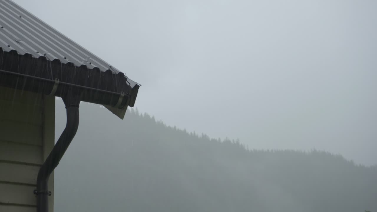 vertiendo agua de lluvia desde el techo de estaño mientras llueve en la región de la colina