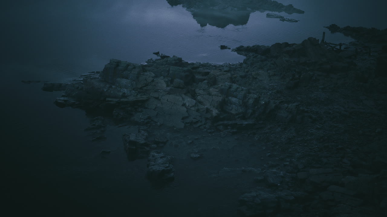 Dark shoreline beside calm water under twilight sky with blurred reflection