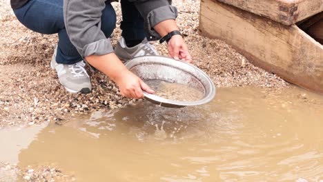 person panning for gold in muddy water