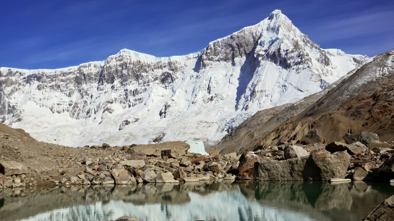 Static view of Mount San Lorenzo in Patagonia with snow-covered slopes mirrored on the still waters of a small glacial lake. Perito Moreno National Park