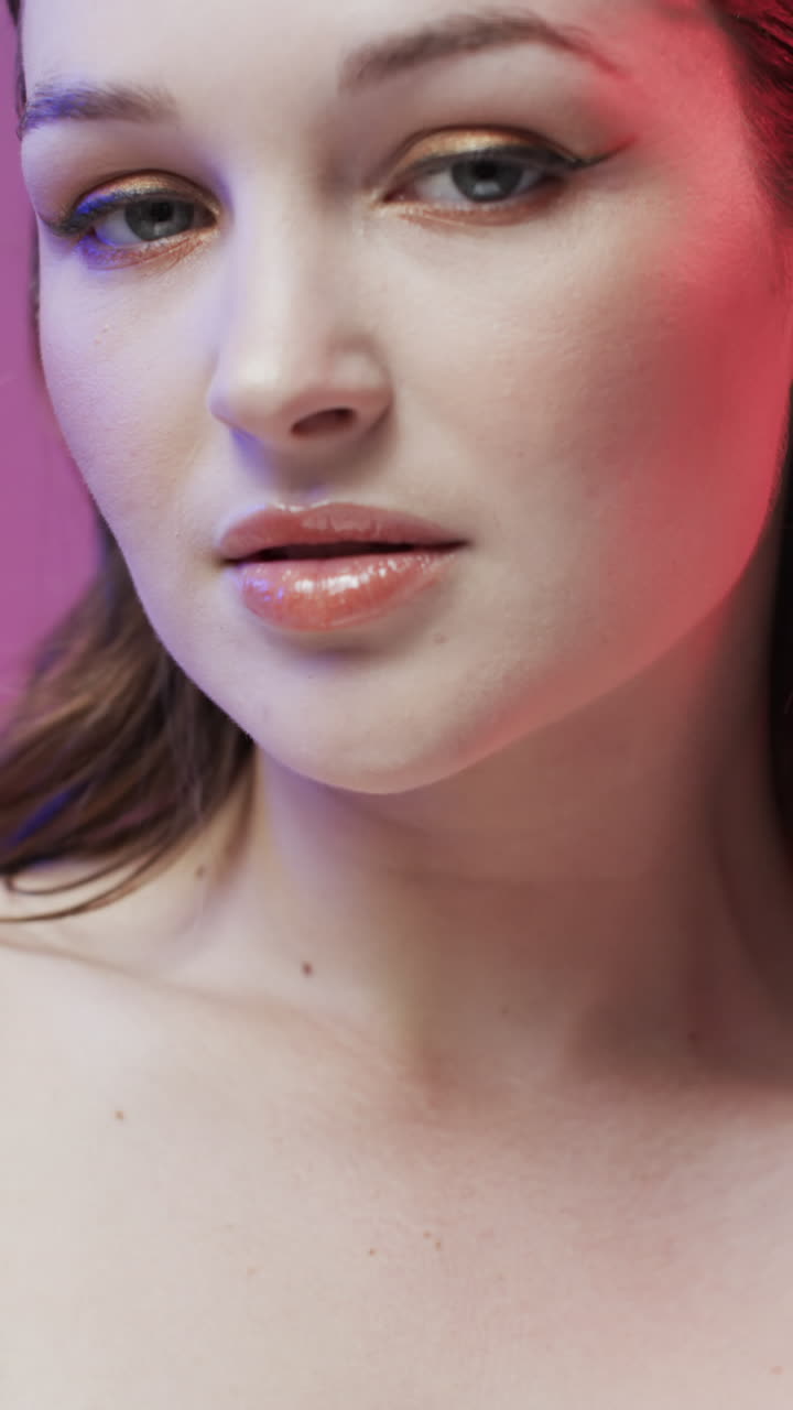 Vertical video of caucasian woman with brown hair and make up touching face, copy space, slow motion