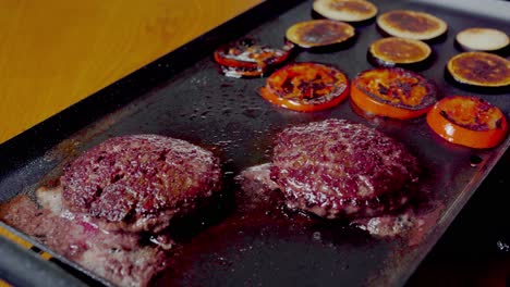 static kitchen scene of smashed burgers and vegetables searing on tabletop grill