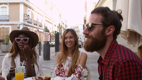 handheld panning shot of friends at a table outside a cafe, shot on r3d